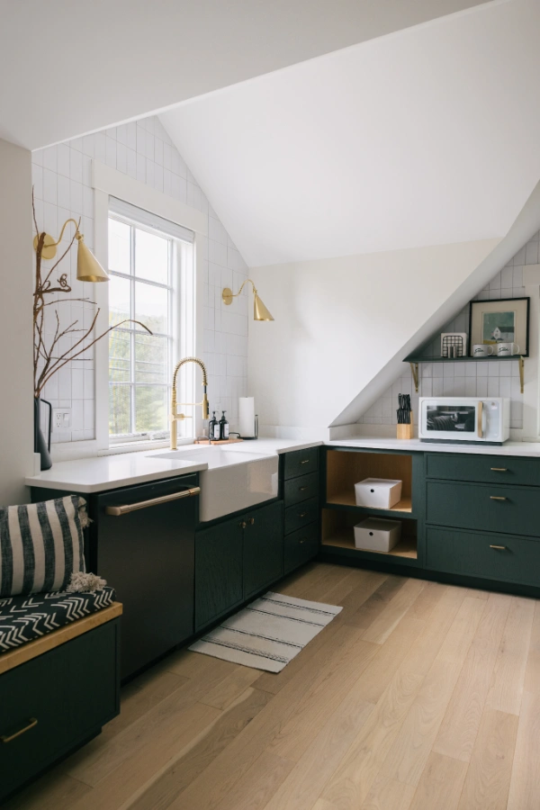 Kitchen workspace featuring farmhouse sink, brass faucet, open shelving, and natural light from a window
